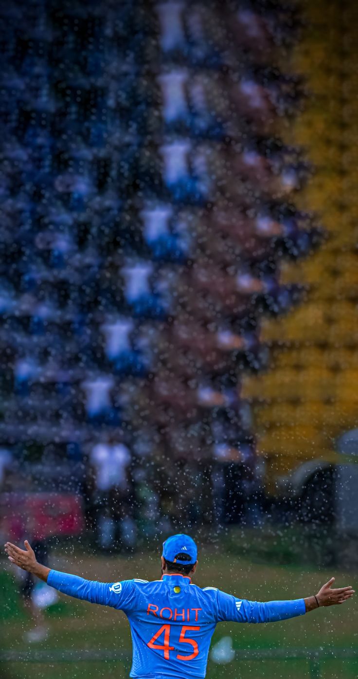 a baseball player throwing a ball in the rain at a game with his arms outstretched