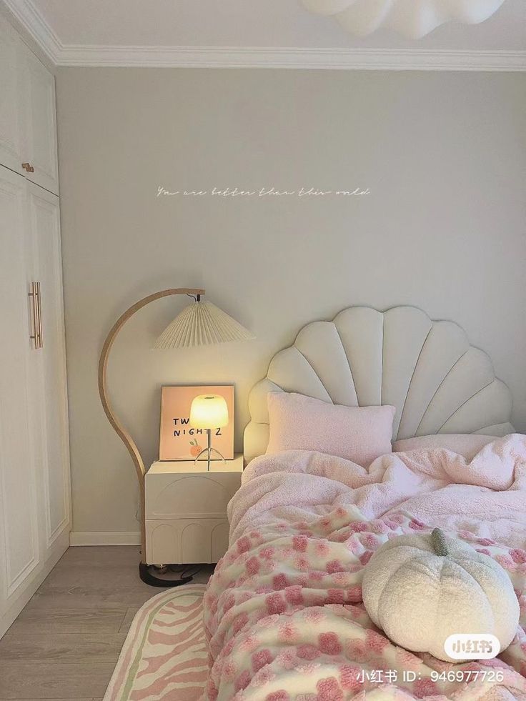 a bed with pink and white bedspread next to a lamp