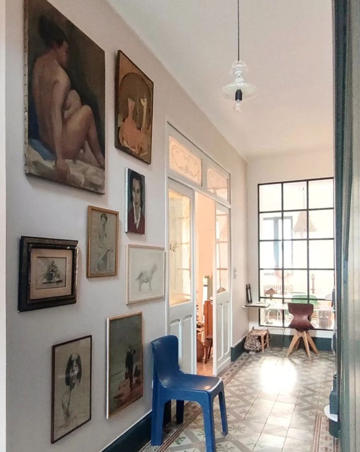 a hallway with pictures on the wall and a blue chair