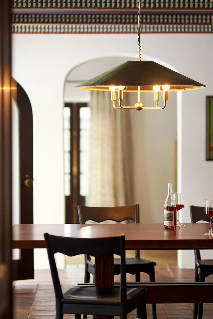 a dining room table with chairs and a light hanging from the ceiling over it's head