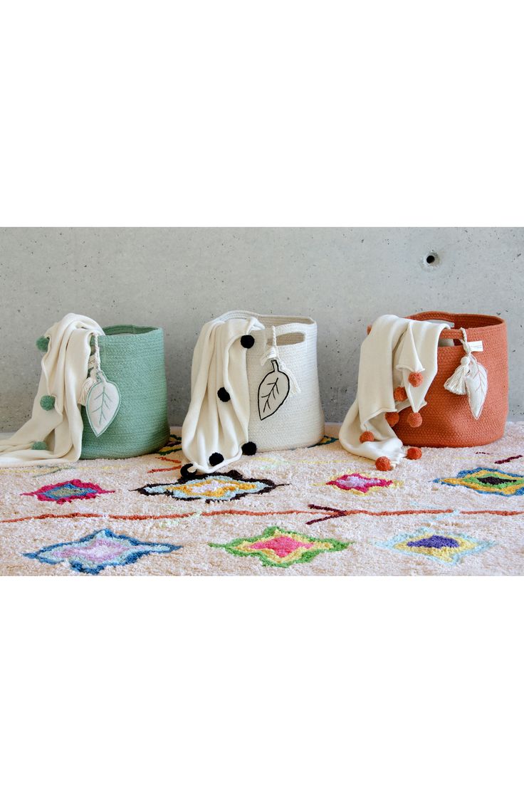 three different colored vases sitting on top of a white table cloth covered floor next to each other