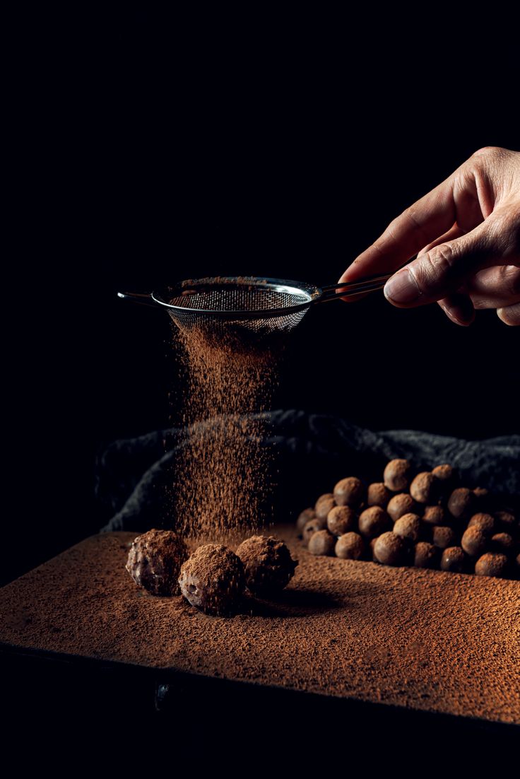 a person is sprinkling nuts with a spoon on top of a table covered in sand