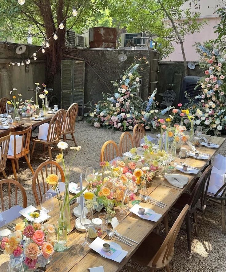 an outdoor dining table set up with flowers and candles on it for a wedding reception