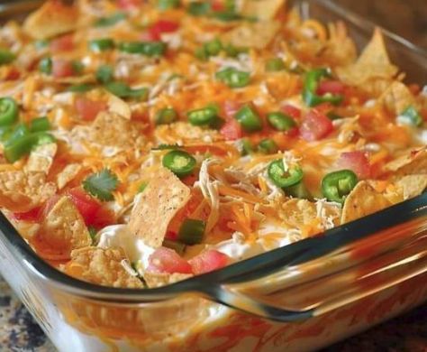 a glass casserole dish filled with nachos and cheese topped with green peppers