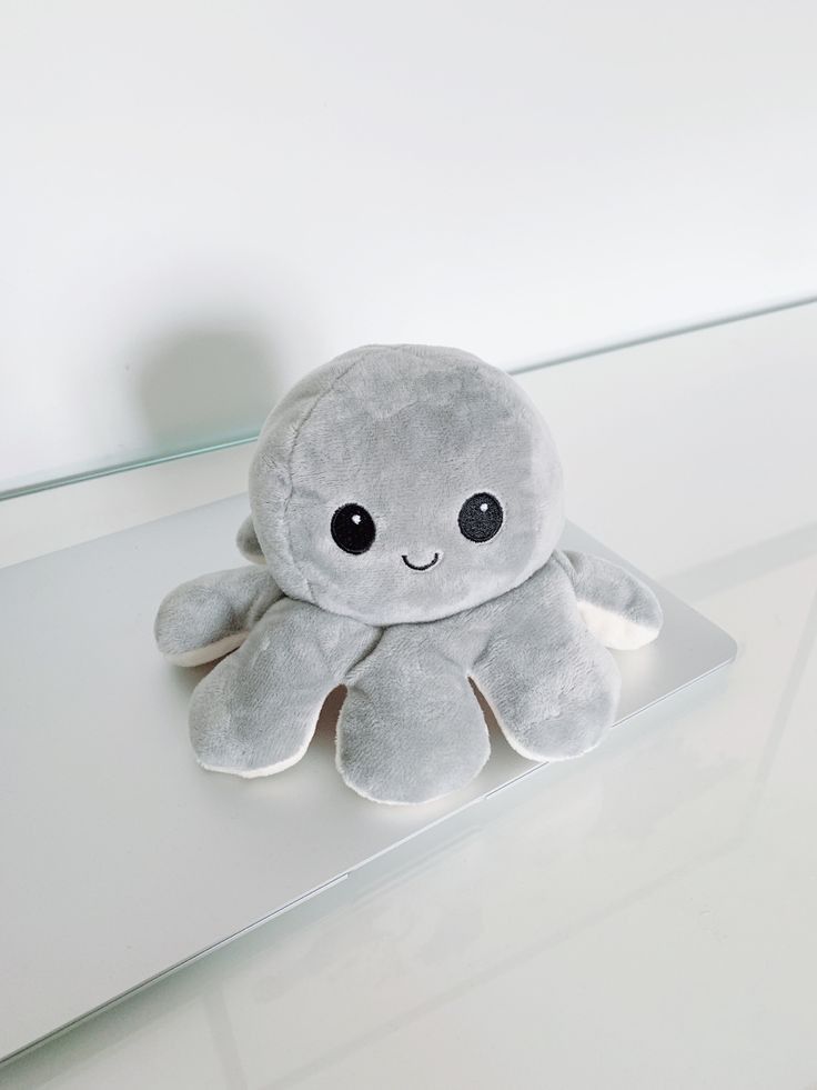 an octopus stuffed animal sitting on top of a glass table next to a white wall