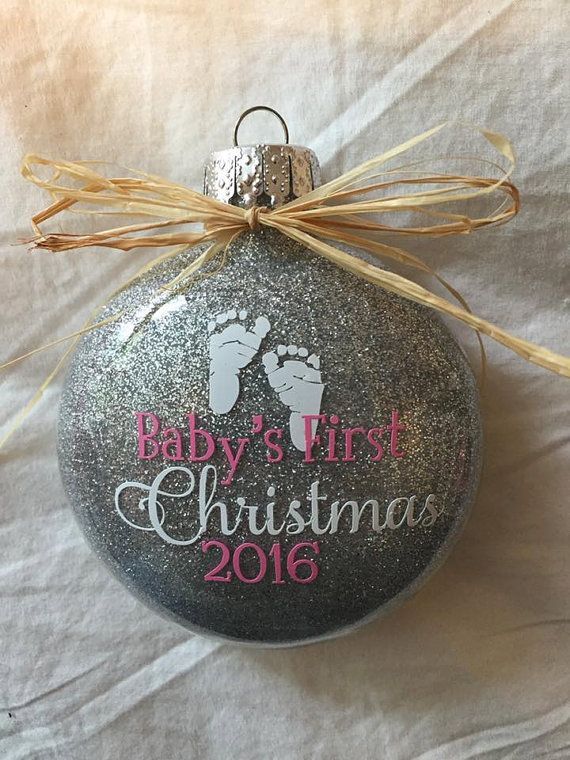 a baby's first christmas ornament hanging from a ribbon