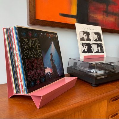 an old record player sitting on top of a wooden dresser next to books and cds