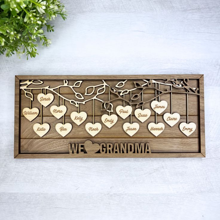 a wooden plaque with hearts hanging from it and the words we love grandma written on it