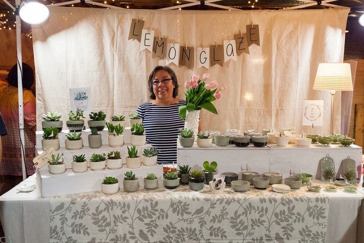 a woman standing in front of a table filled with potted plants