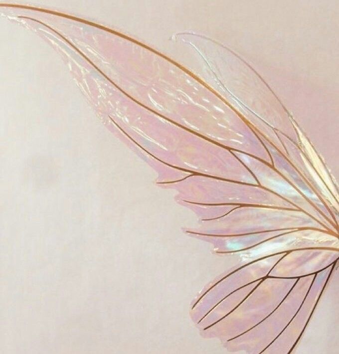 a close up of a leaf shaped object on a white surface with light pink background