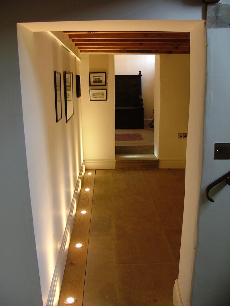 an empty hallway with lights on the floor and pictures hanging on the wall behind it