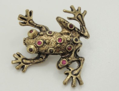 a gold colored frog brooch with pink stones