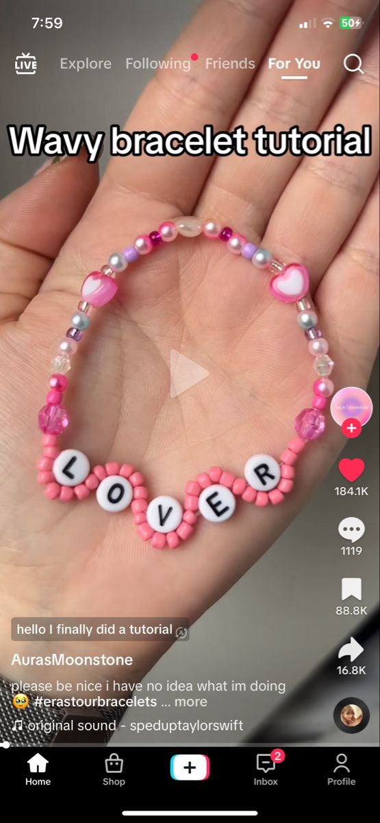 a hand holding a pink beaded bracelet with words that spell out love on it