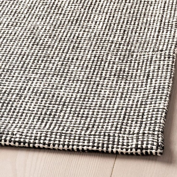 a black and white checkered rug sitting on top of a wooden floor