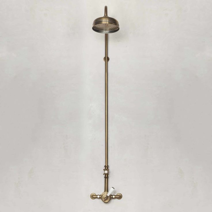 an antique brass wall light on a white wall in a room with no one around it