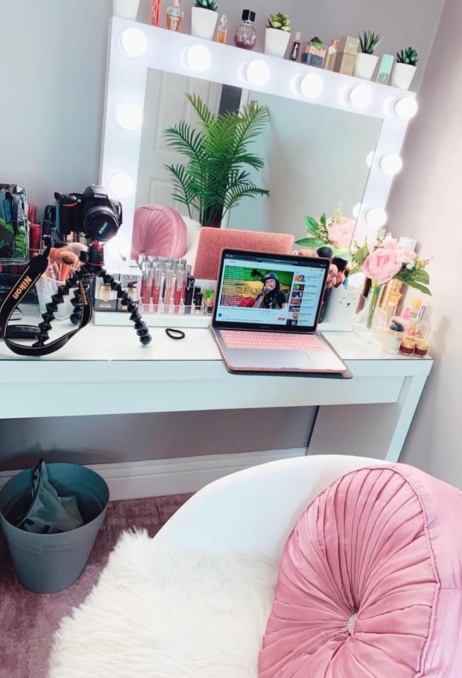 a laptop computer sitting on top of a white desk next to a chair and mirror