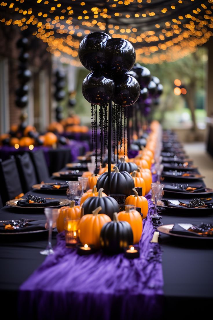 a long table is set with black and orange balloons, candles, and plates for an elegant halloween party