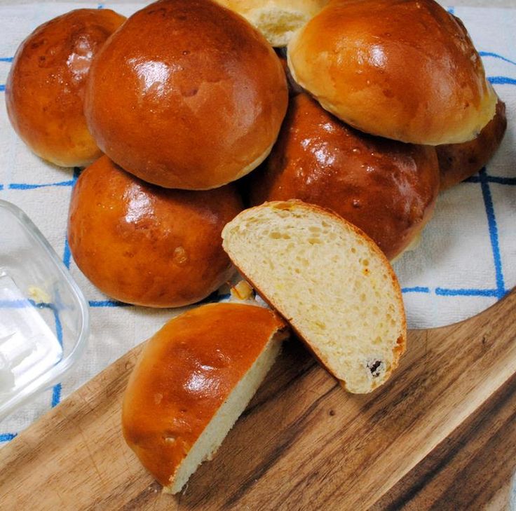 a pile of bread rolls sitting on top of a wooden cutting board