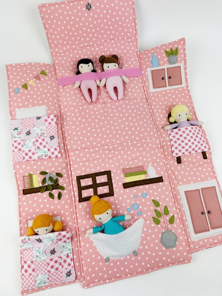 a doll house made out of pink fabric with dolls on the top and bottom floor