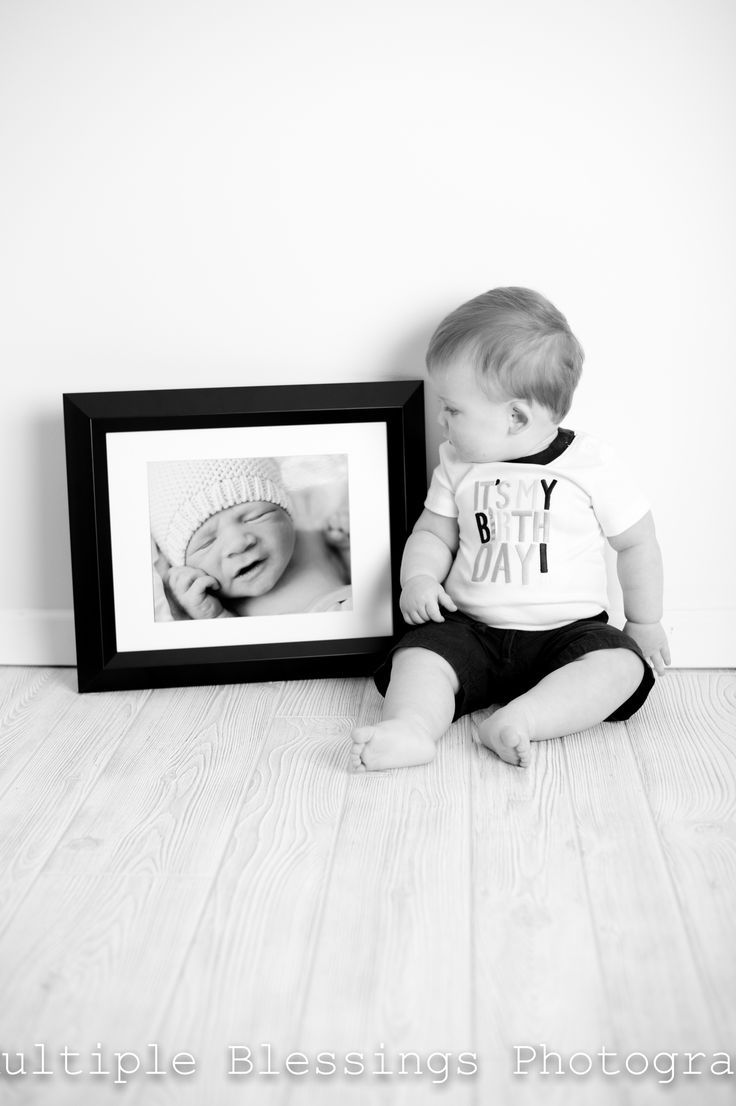 a black and white photo of a baby sitting next to a frame