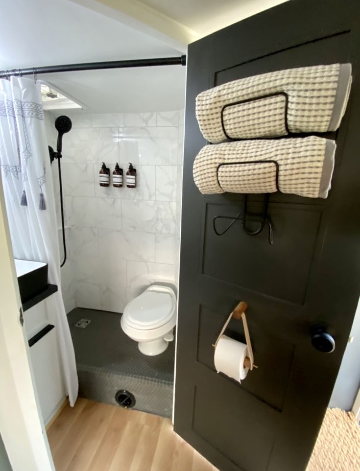 a bathroom with toilet, shower and towel rack