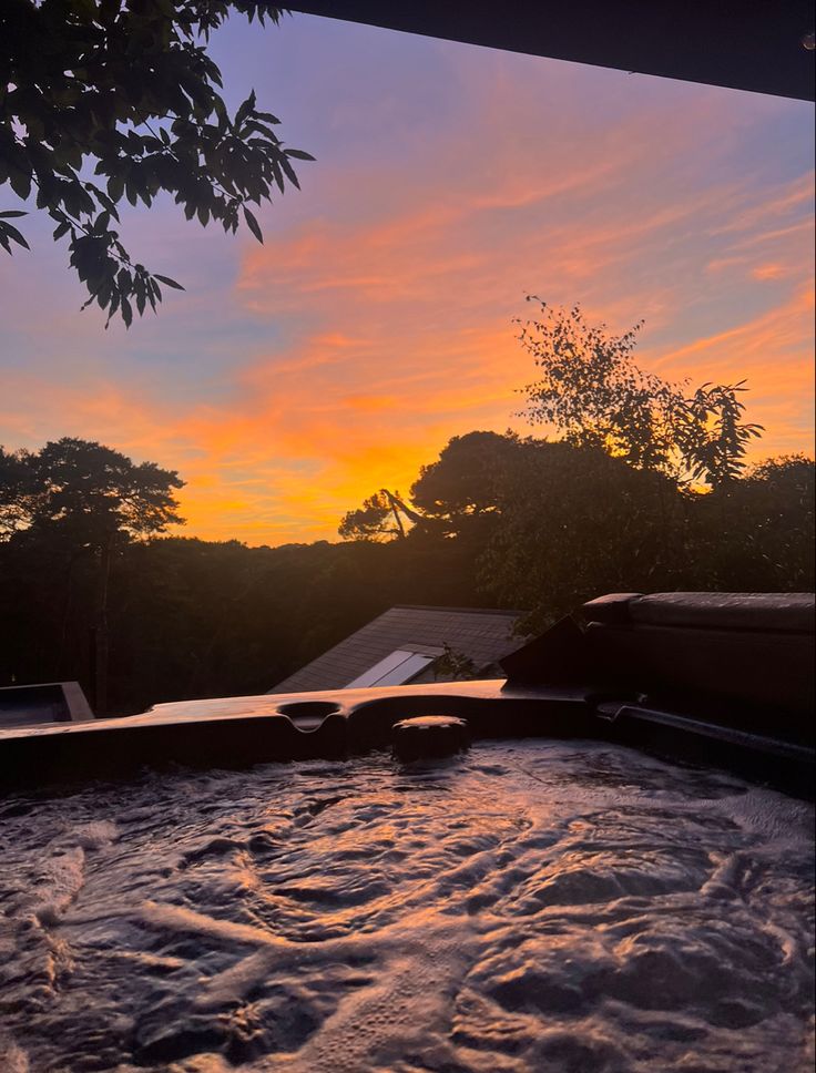 a hot tub with the sun setting in the background