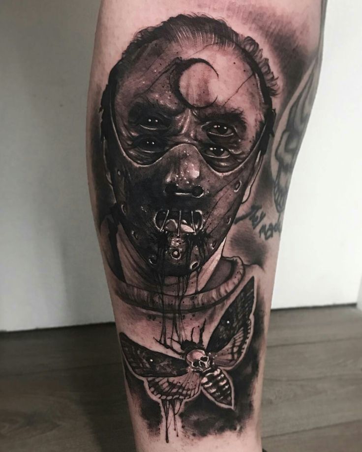 a man's leg with a black and grey tattoo on it