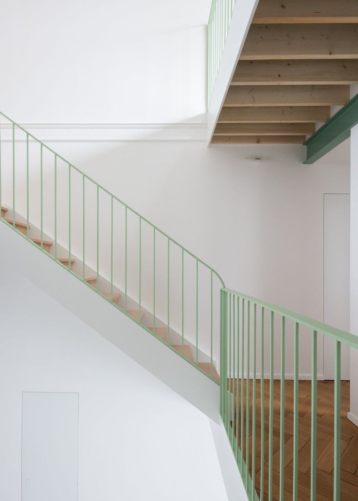 an empty room with green railings and wood flooring on the second floor, next to a white wall