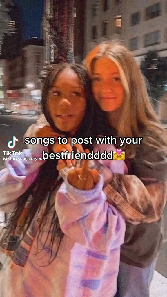 two young women hugging each other on the street