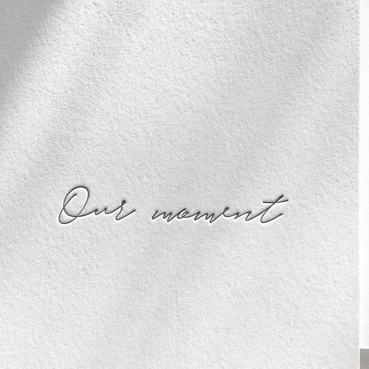 the word our moment written in cursive handwriting on a white paper background with shadow