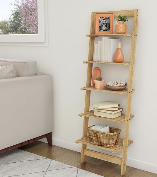 a tall wooden shelf with books and vases on it in the corner of a living room