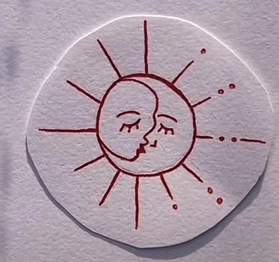 a sticker with a drawing of a sun and a face in red ink on white paper