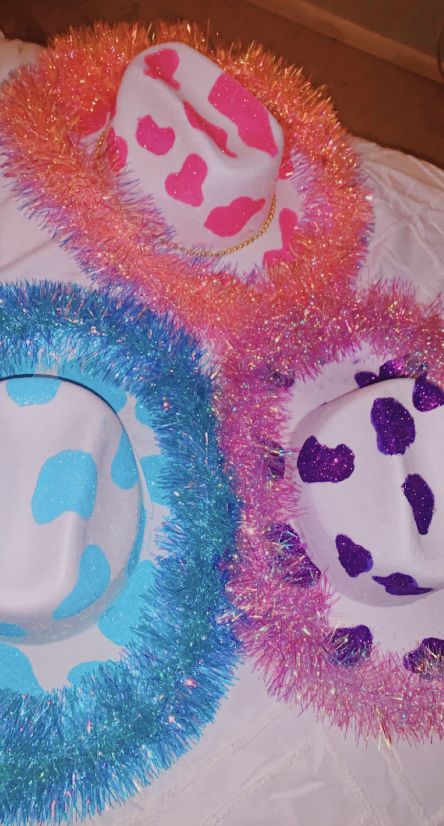 three hats are sitting on a table with pink and blue tinsel around the edges