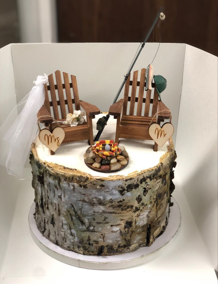 a wedding cake with two wooden chairs on top of it and a fishing rod in the middle