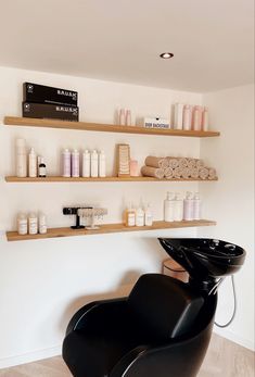 a salon chair in front of shelves filled with hair products and personal care items on the wall