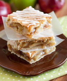 two pieces of apple pie sitting on top of a brown plate next to an apple