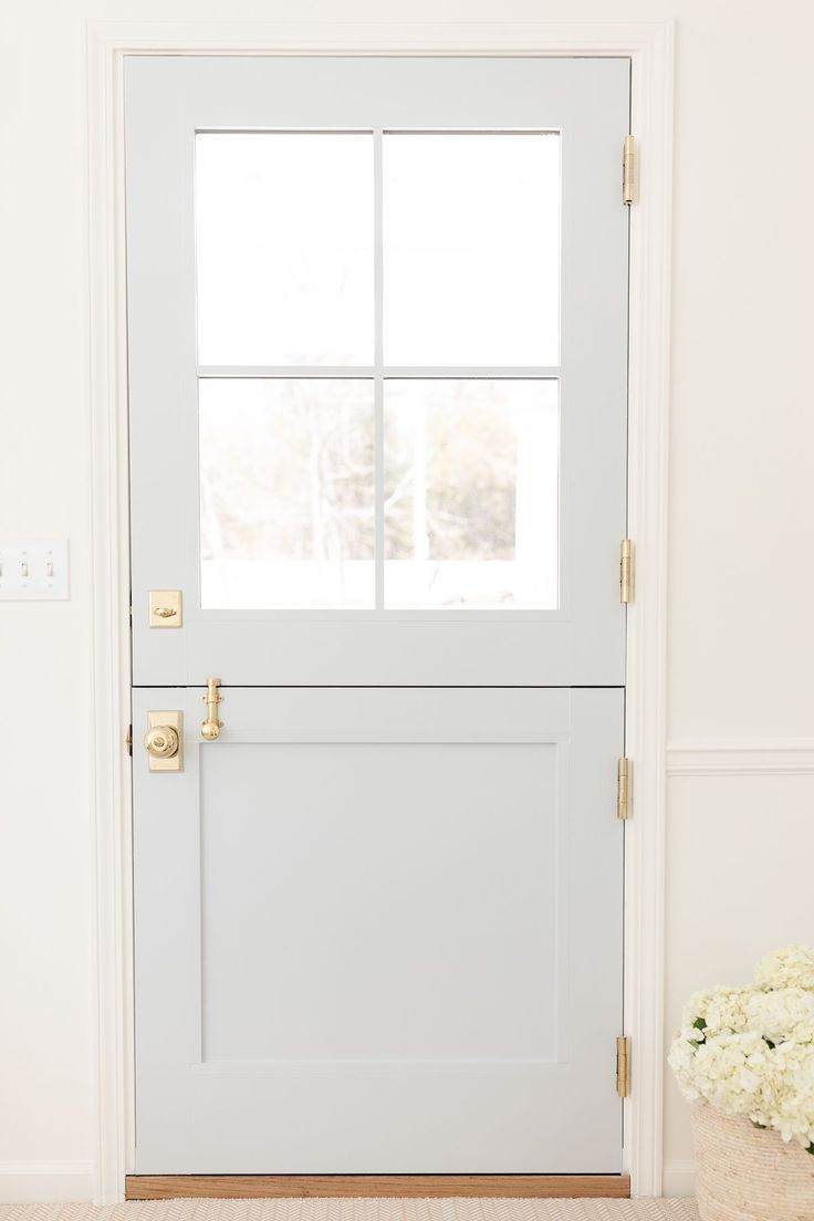 a white front door with two windows and a basket full of flowers on the floor