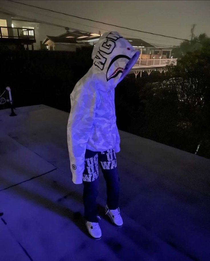 a person wearing a white jacket and blue pants is standing on the sidewalk with their arms in the air