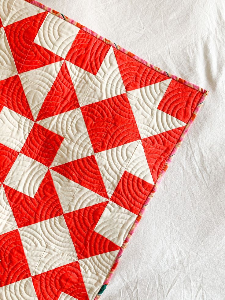 a red and white quilt on top of a table