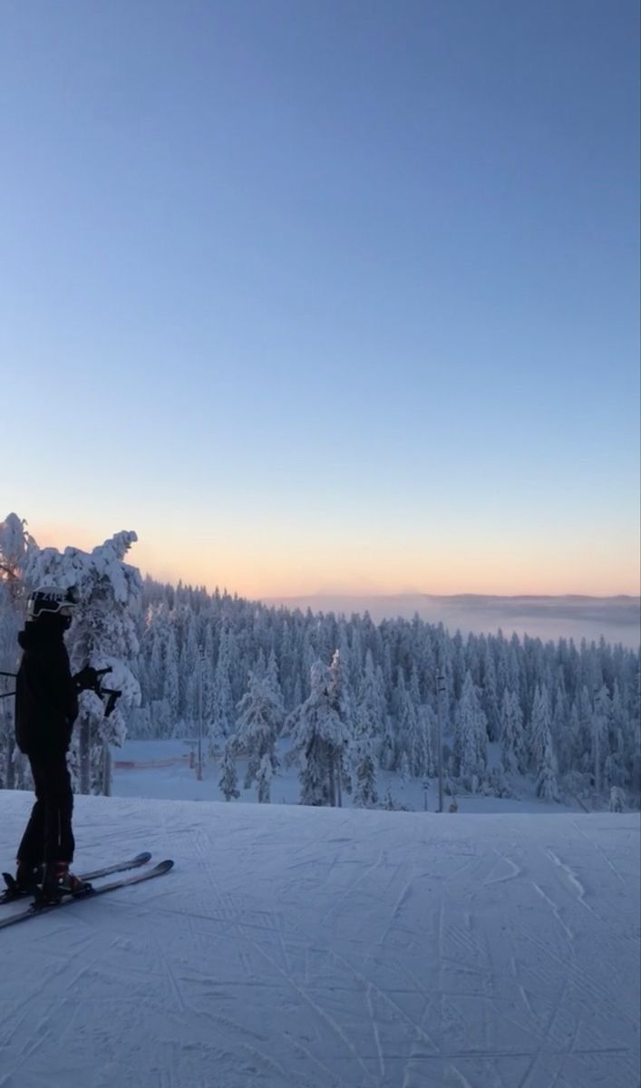 a person riding skis on top of a snow covered slope in the sun setting