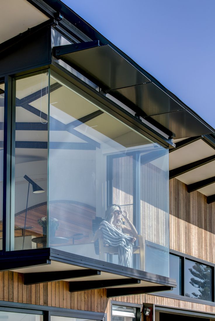 a person sitting in a chair on top of a glass balcony next to a building