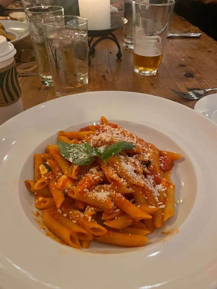 pasta with sauce and parmesan cheese on a white plate at a restaurant table