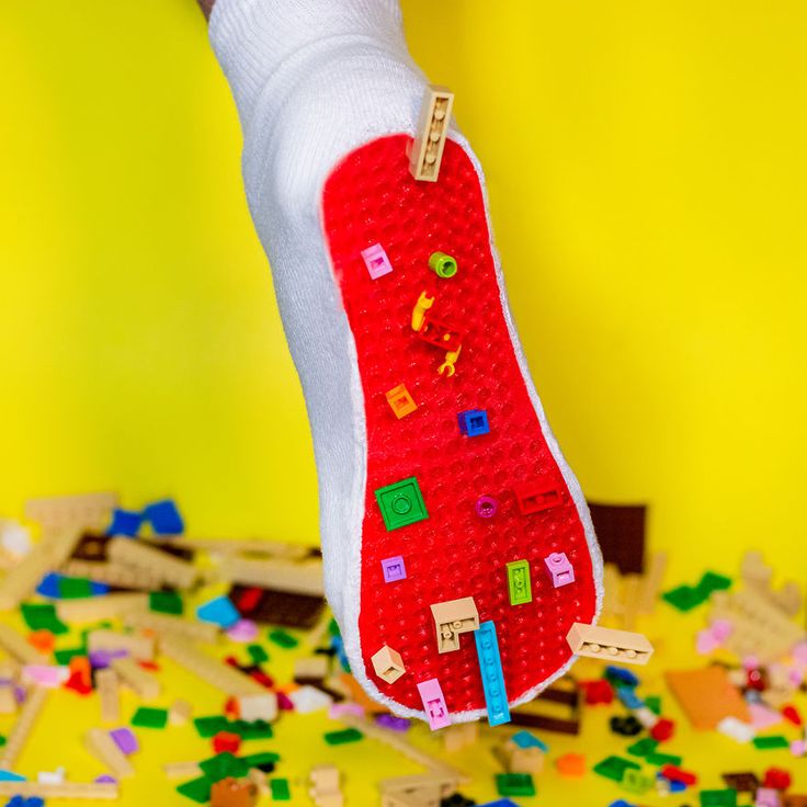 a person holding up a red object made out of legos on a yellow background