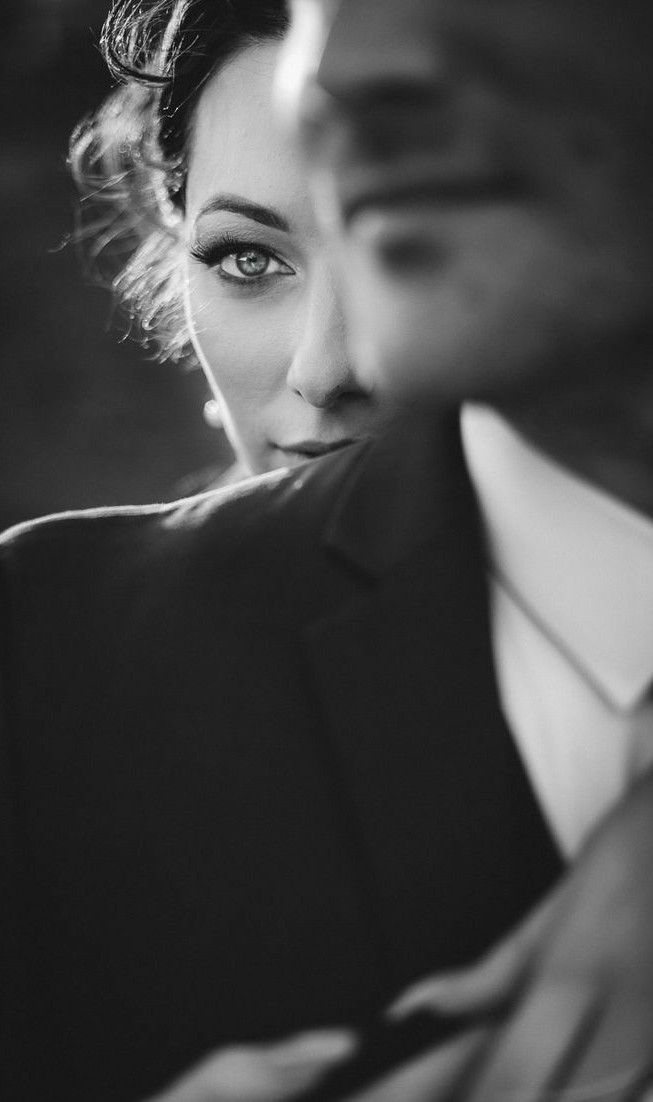 a black and white photo of a woman in a suit with her hand on her shoulder