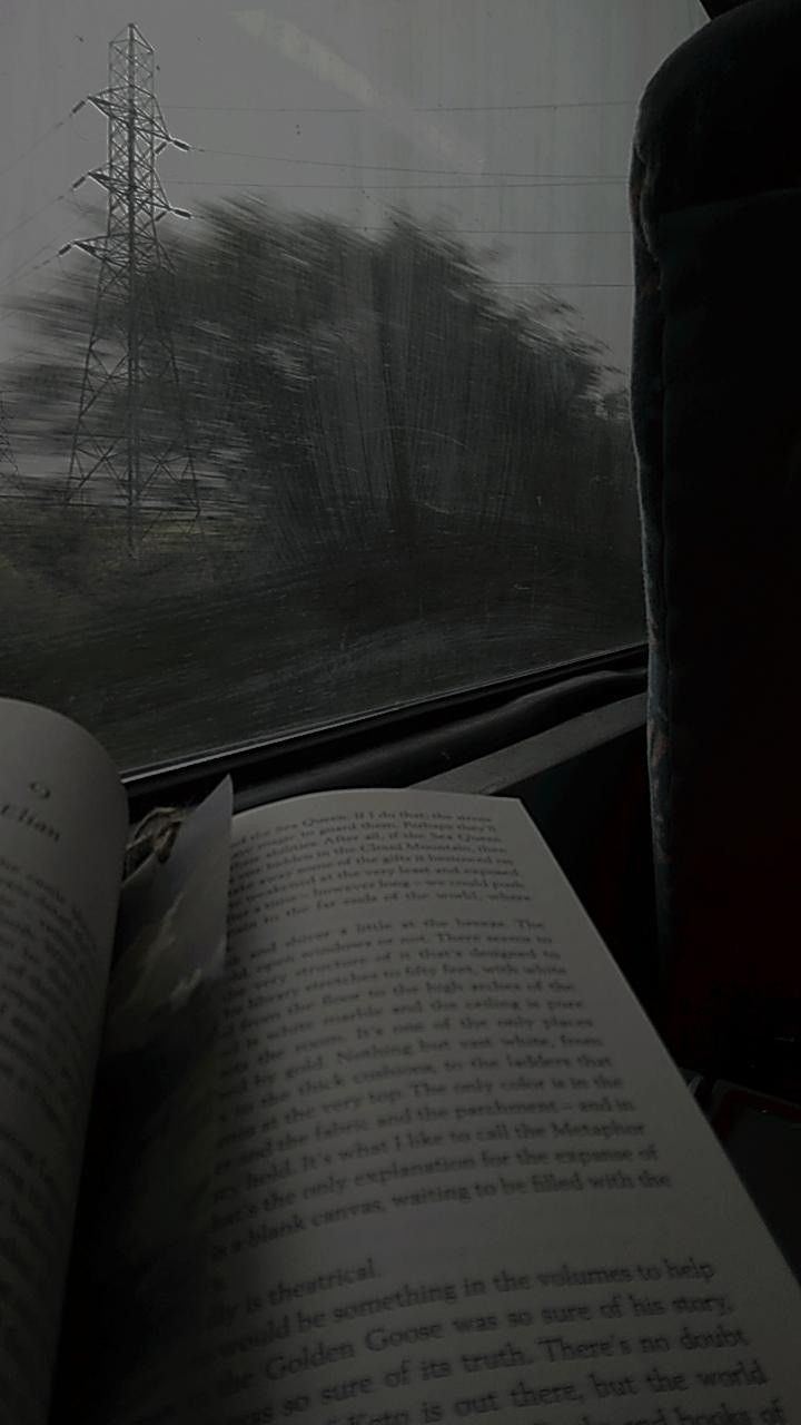 an open book sitting on top of a table next to a window with power lines in the background