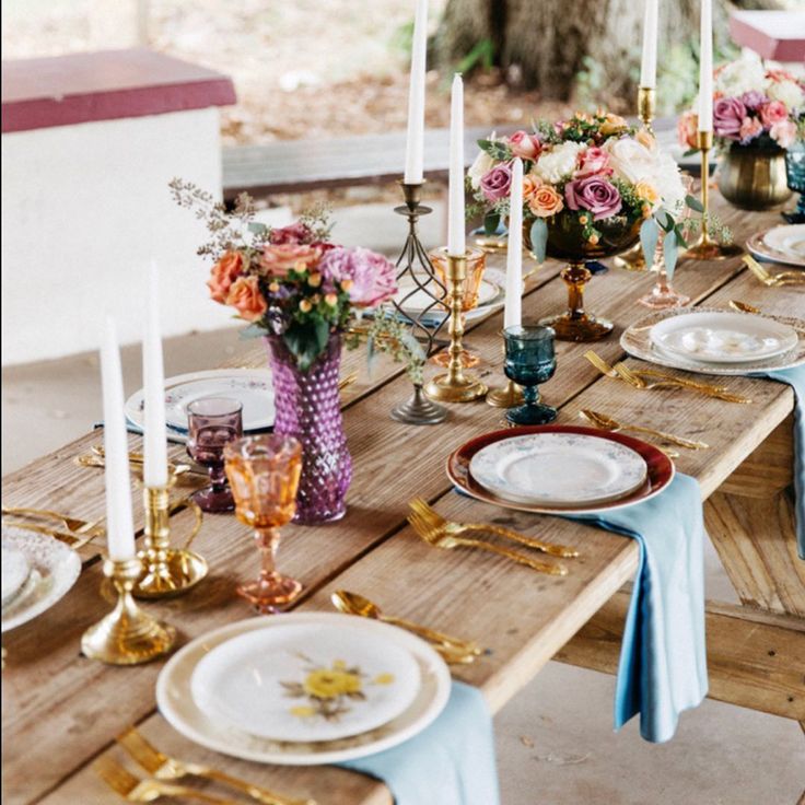 an outdoor table set with plates and place settings