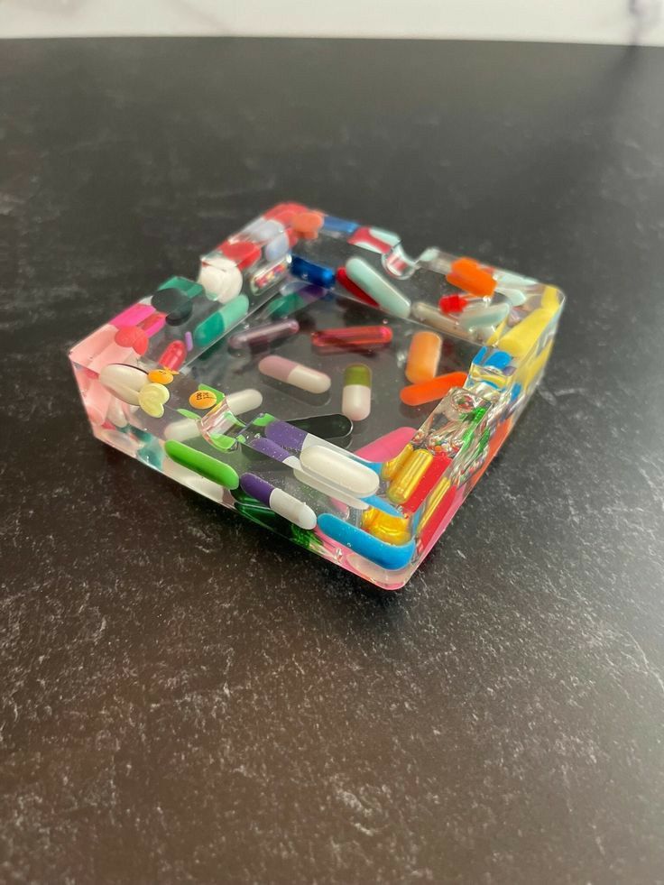 an assortment of colorful toothbrushes in a clear container on a black counter top