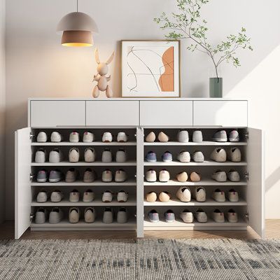 a white cabinet with many pairs of shoes on the bottom shelf in front of it