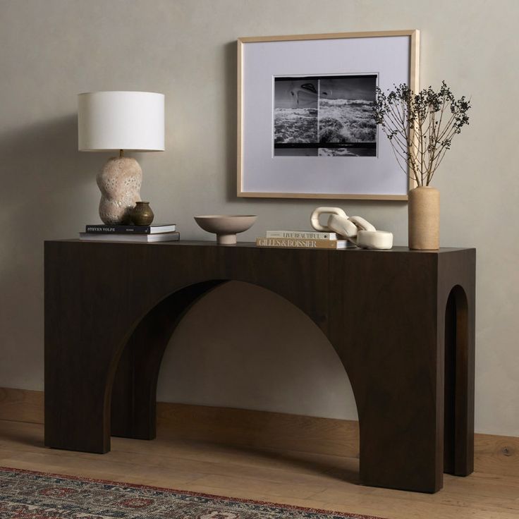 a wooden table with vases and other items on it next to a framed photograph