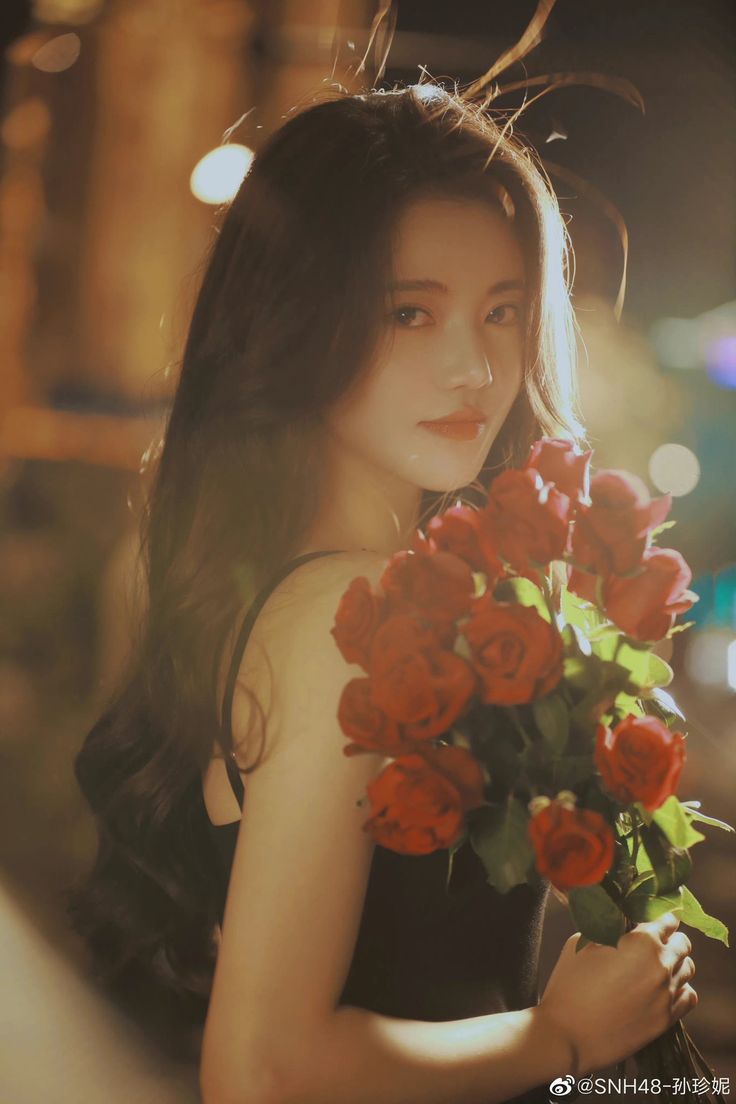 a young woman holding a bouquet of red roses